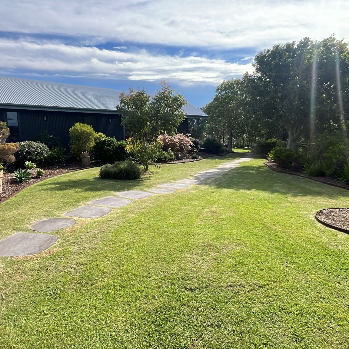 Maintained lawn and garden beds beside a rural home