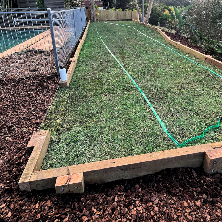 New turf laid inside timber sleeper edging beside a pool